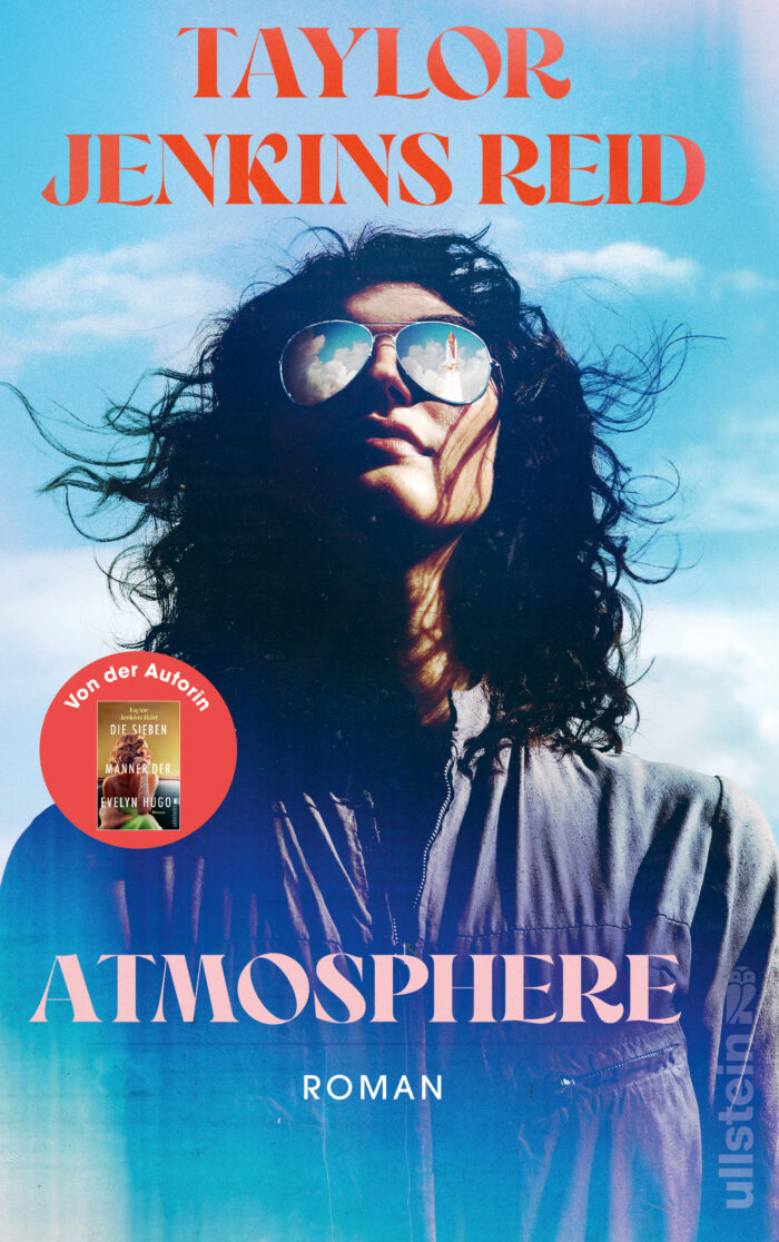 Cover von „Atmosphere“ von Taylor Jenkins Reid: Eine Person mit langen, lockigen Haaren trägt Sonnenbrillen und blickt nach oben, der Hintergrund zeigt einen blauen Himmel.